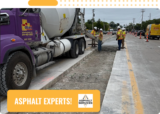 Workers in safety gear pour concrete from a cement truck onto a sectioned-off road area under construction. Traffic cones line the street. Text at the bottom reads “ASPHALT & CONCRETE SERVICES EXPERTS!” with the Asphalt Services logo.